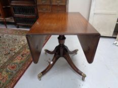 An inlaid mahogany pedestal flap sided dining table