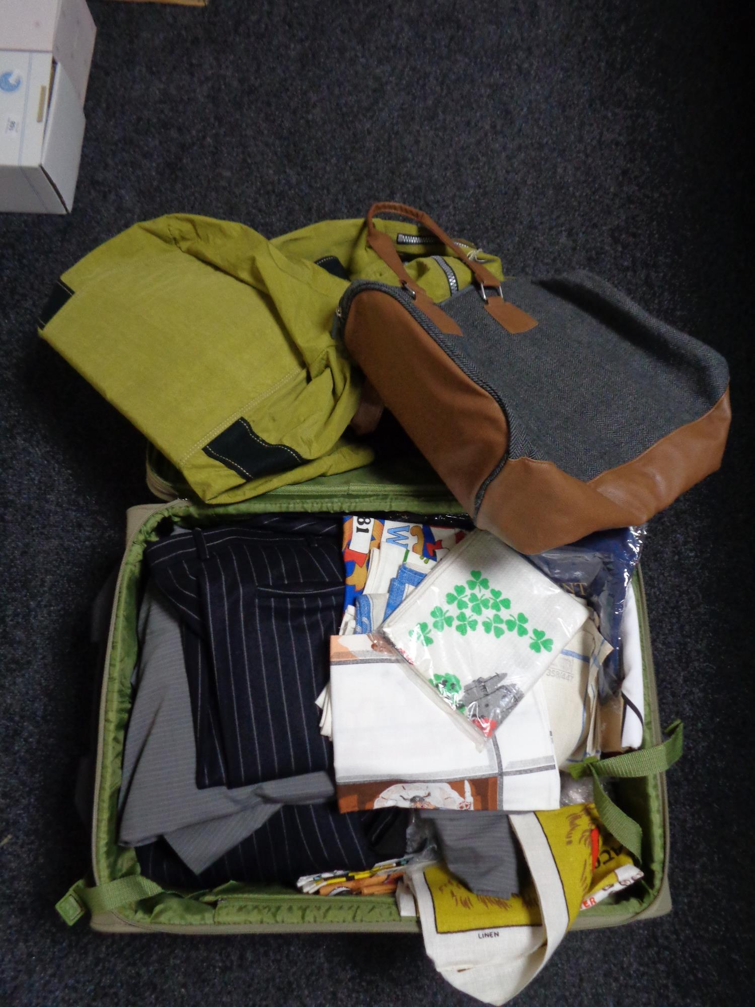 A luggage case and a holdall of clothing, new tea towels,