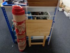 A red Chinese fringed rug, clothes airer and a folding table.