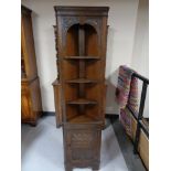 A carved oak corner display stand fitted a cupboard beneath