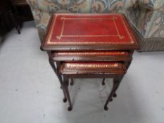 A nest of three mahogany leather topped tables