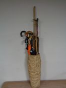 A wicker stick pot containing walking sticks and umbrellas