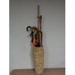 A wicker stick pot containing walking sticks and umbrellas