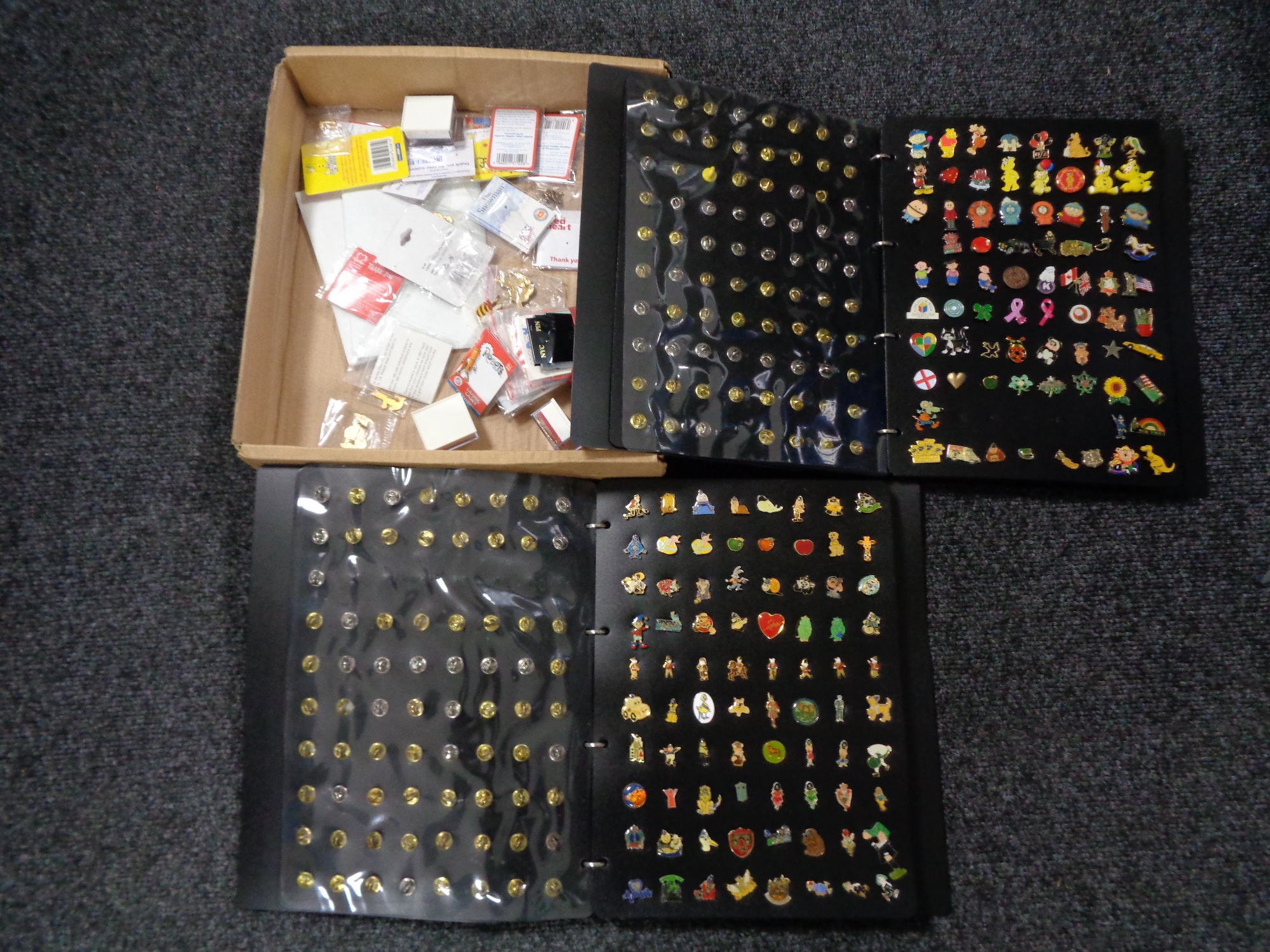 A collection of enamelled pin badges in a folder and loose,