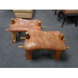 A pair of camel stools with leather saddles