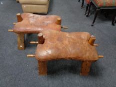 A pair of camel stools with leather saddles