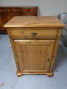 A pine single door cabinet fitted with a drawer