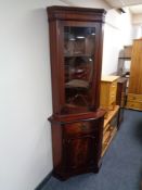 A glazed corner display cabinet in mahogany finish