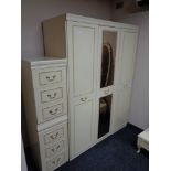 A cream and gilt triple door wardrobe together with a pair of three drawer bedside chests