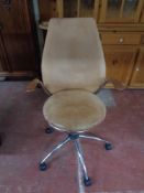 A tan leather swivel chair on chrome base