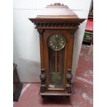 An early twentieth century beech wall clock with pendulum and brass dial