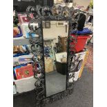 A cotemporary bevel-edged hall mirror, in an elaborate black metal foliage design frame,