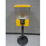 A revolving four sided coin operated sweet dispenser on metal pedestal