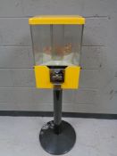 A revolving four sided coin operated sweet dispenser on metal pedestal