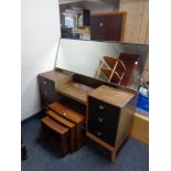 A mid century teak knee hole dressing table with headboard together with a further nest of teak