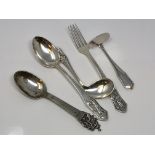 A highly ornate silver spoon and a four piece christening set depicting scenes from folklore signed,