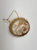 An ornate gold cameo brooch with gold safety chain