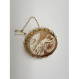 An ornate gold cameo brooch with gold safety chain