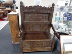 An antique carved oak storage seat, the carved back depicting figures,