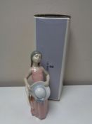 A Lladro figure - Girl holding hat in peach dress, boxed.