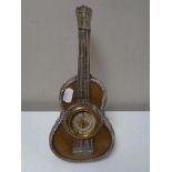 An ornate white metal table barometer in the form of a guitar