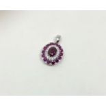 A 14ct white gold ruby and diamond pendant, featuring centre oval cut ruby (1.