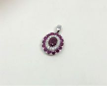 A 14ct white gold ruby and diamond pendant, featuring centre oval cut ruby (1.