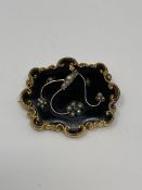 A Victorian mourning brooch highlighted with seed pearls on yellow metal and black glass,