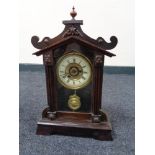 An early twentieth century stained beech alarm clock with pendulum