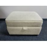 An upholstered oatmeal fabric storage stool