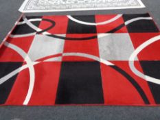 A contemporary machine made carpet with red and black design