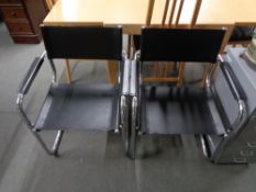 A pair of tubular metal chairs with stitched black leather sling type seats