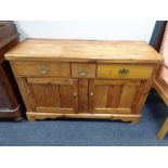 An antique pine sideboard fitted with three drawers, height 80 cm, width 127 cm and depth 44 cm.