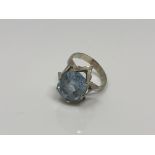 A continental white metal ring, the textured collet set with an oval blue stone, size N/O,