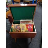 A mid century cabinet with lift top containing vinyl records