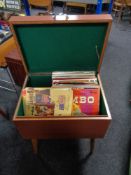 A mid century cabinet with lift top containing vinyl records