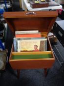 A mid century cabinet with lift top containing vinyl records