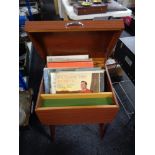 A mid century cabinet with lift top containing vinyl records