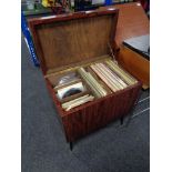 A mid century cabinet with lift top containing vinyl records