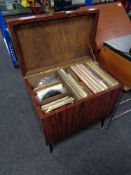 A mid century cabinet with lift top containing vinyl records