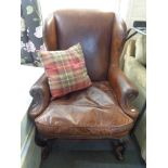 An antique style brown studded leather armchair with cushion