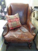 An antique style brown studded leather armchair with cushion