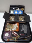 A tray of antique metal cash box, letter opener, large quantity of foreign coins, military badges,