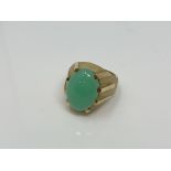 A continental yellow gold ring, the textured shank set with a cabochon apple green jade stone,