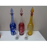 Three cut crystal coloured decanters together with a pair of nineteenth century etched glass
