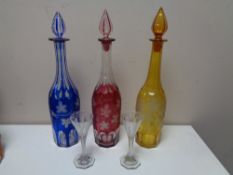 Three cut crystal coloured decanters together with a pair of nineteenth century etched glass