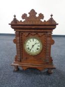 An Edwardian oak mantel clock with enamel dial by the Ansonia clock company