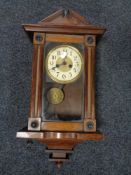An Edwardian stained beech wall clock with pendulum