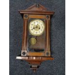 An Edwardian stained beech wall clock with pendulum