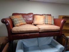 A burgundy leather and red fabric settee with scatter cushions